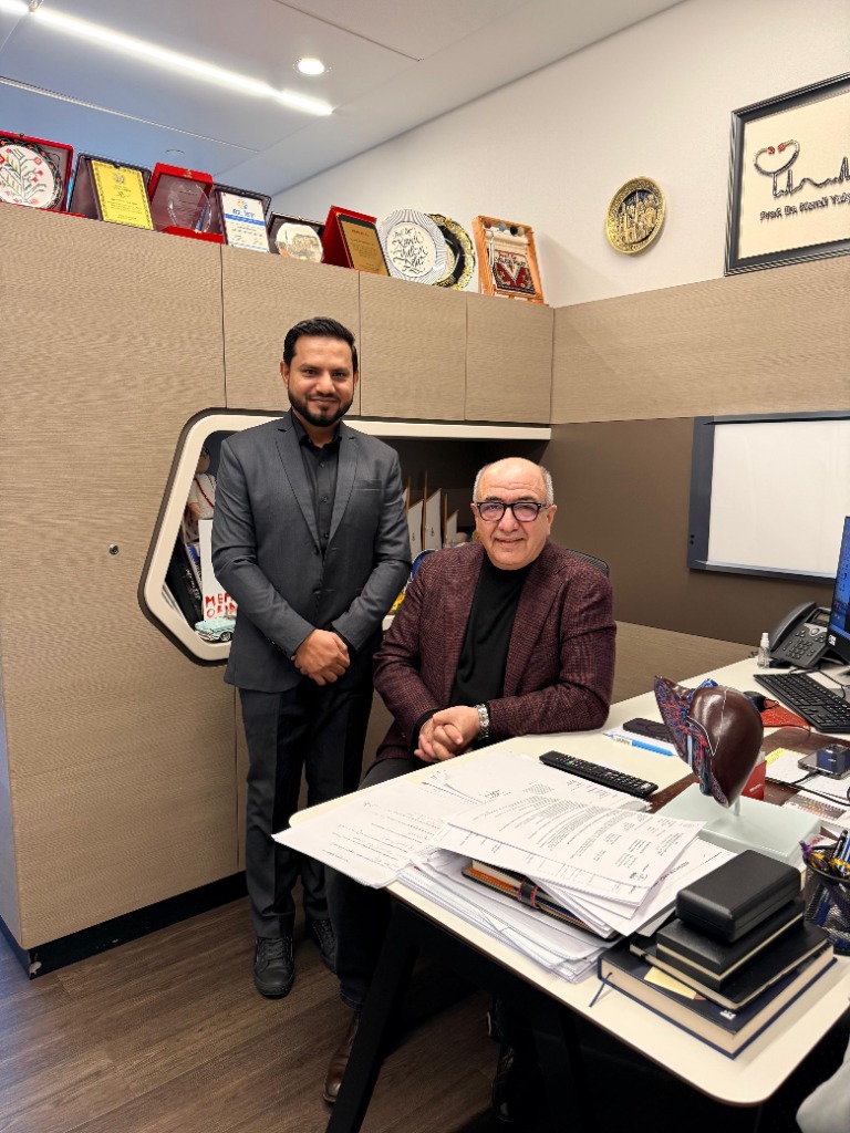 Ajaz Ahmad standing beside a colleague seated at an office desk
