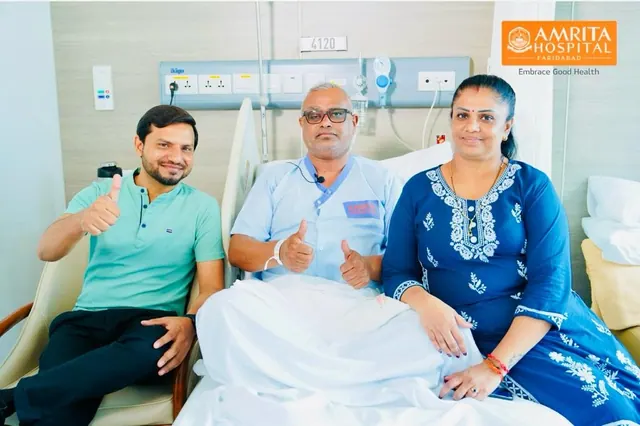 A patient in a hospital bed, with two people beside him